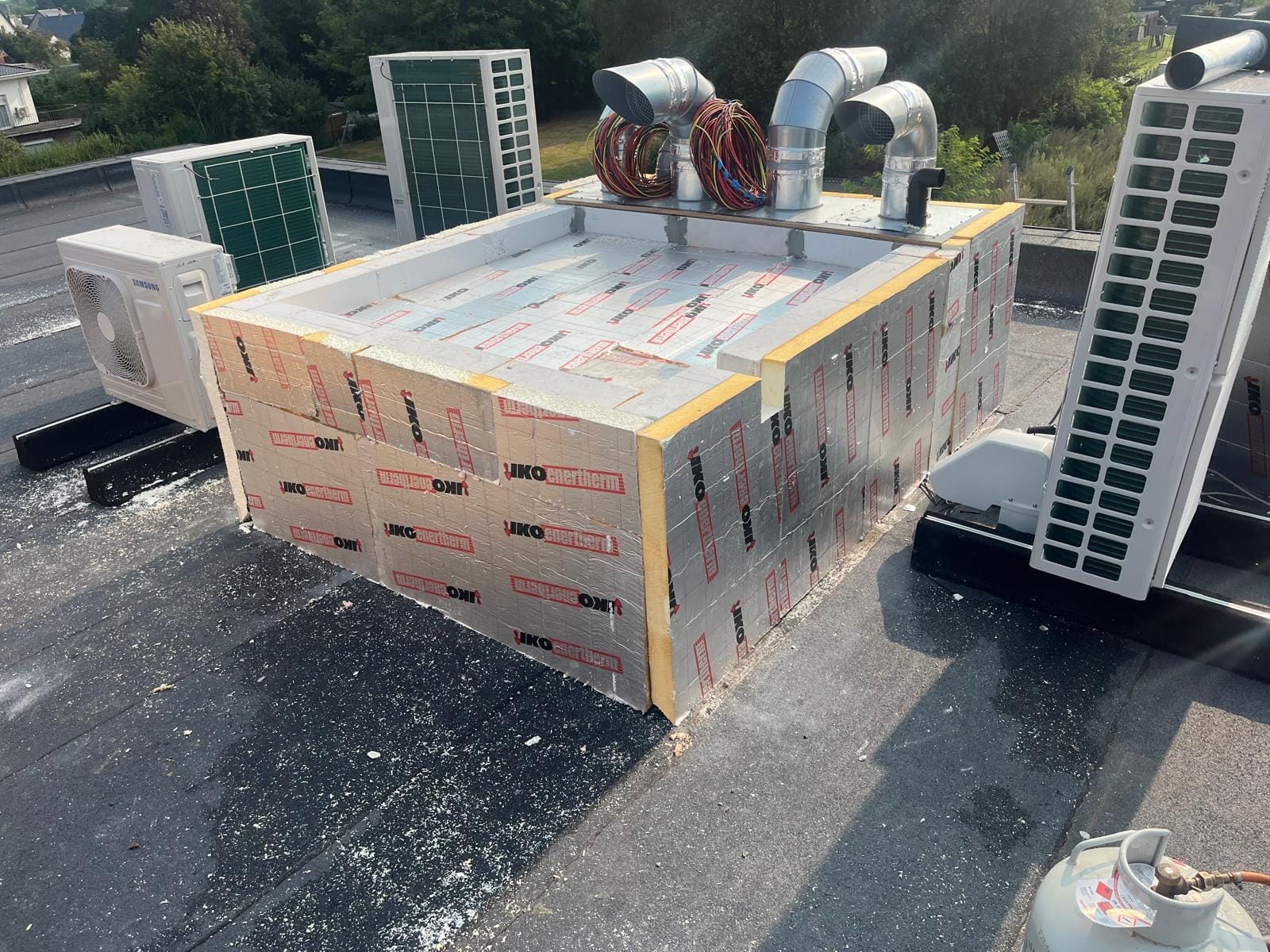 Dakopbouw voor installaties in ruwbouw, met isolatieplaten en losse leidingen.