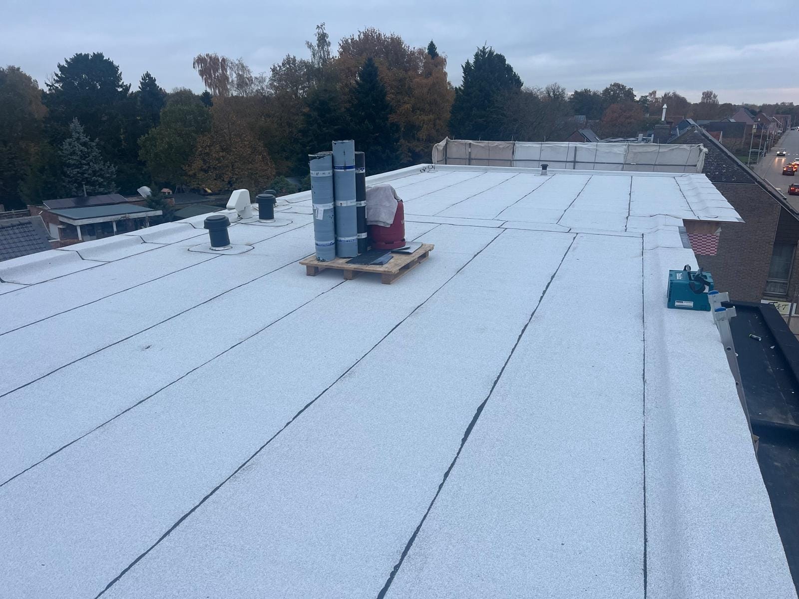 Afgewerkt bitumendak met minerale toplaag, met het dorp en de kerktoren op de achtergrond.