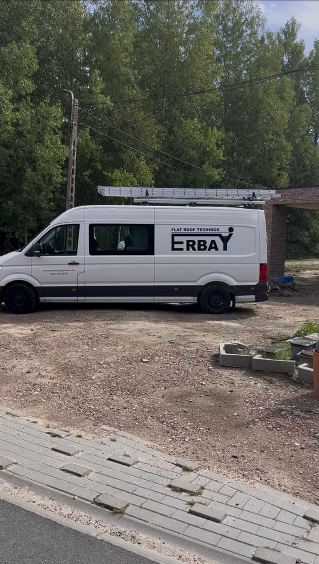 De bestelwagen van Erbay Flatroof Technics met bedrijfsbelettering, geparkeerd op een werf.