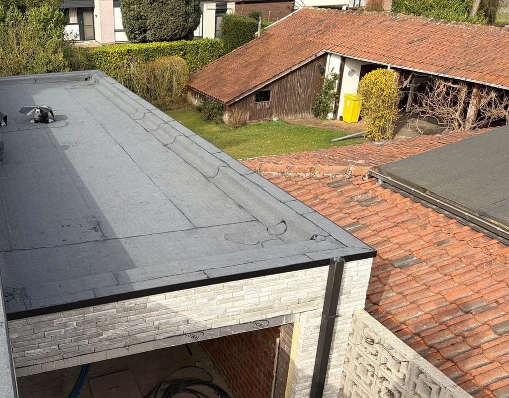 Afgewerkt EPDM-dak op een aanbouw, van bovenaf gezien, met omliggende tuinen en pannendaken.
